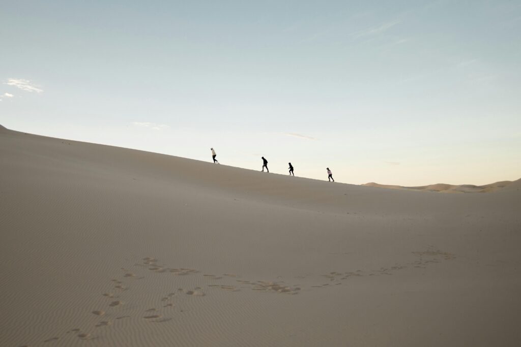 A group of people hiking at sunrise in the Samalayuca Desert, Mexico.