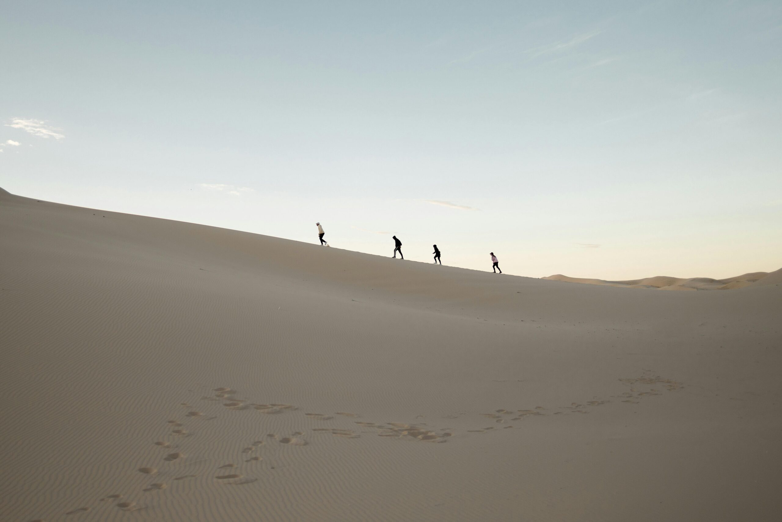 A group of people hiking at sunrise in the Samalayuca Desert, Mexico.